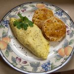 An omelet with fresh herbs plated with a buttered English muffin