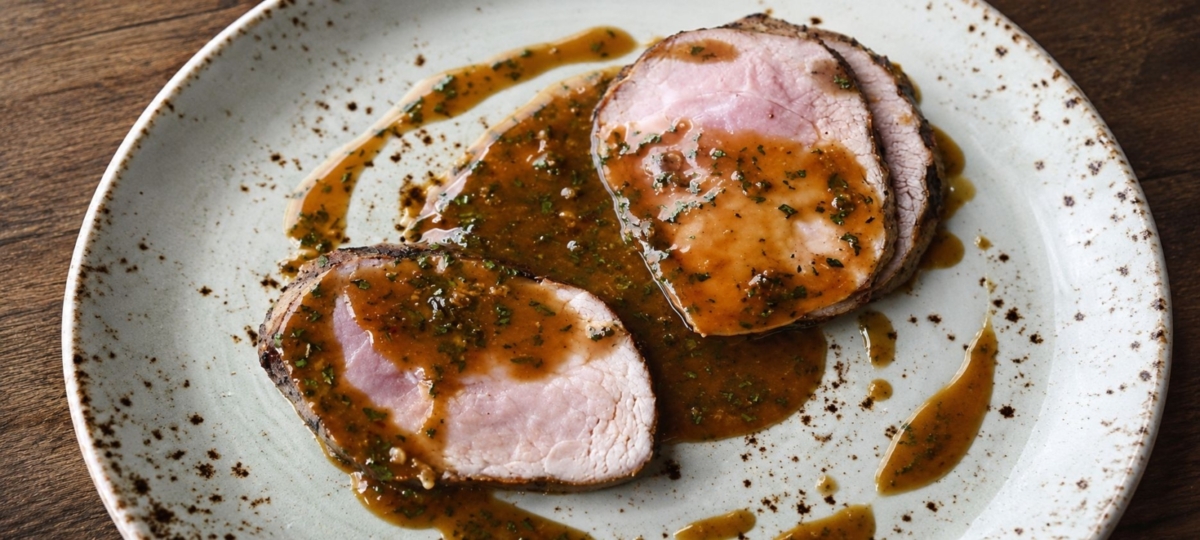 Plated pork tenderloin slices with green peppercorn sauce.