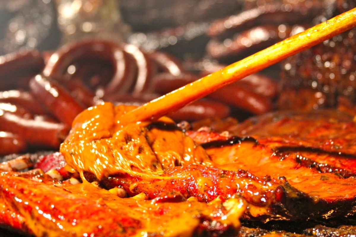 meat being brushed with mop sauce