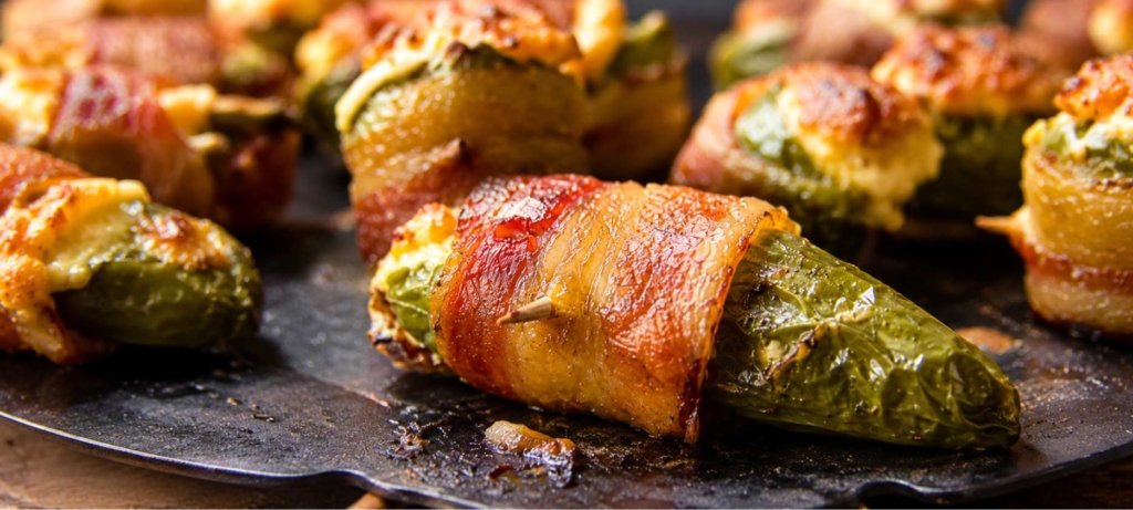 Bacon wrapped jalapeno poppers on a black plate