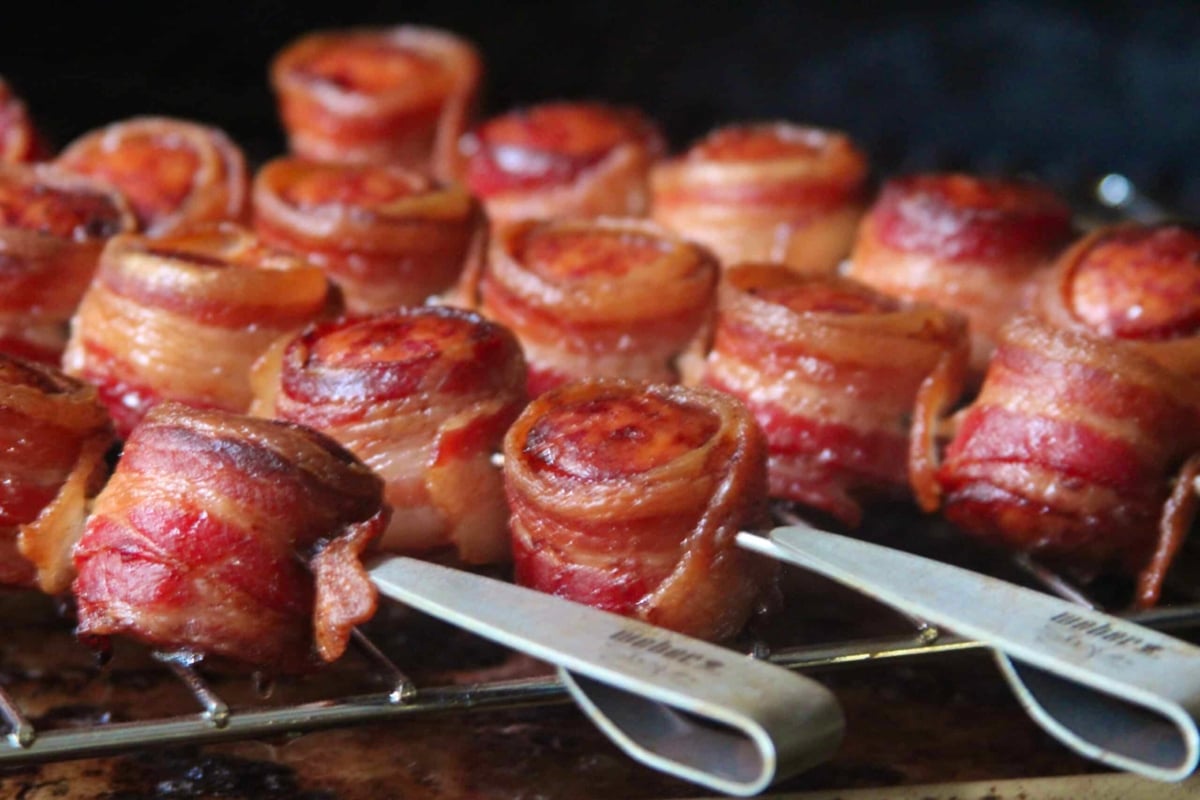 bacon wrapped kielbasa on a grill