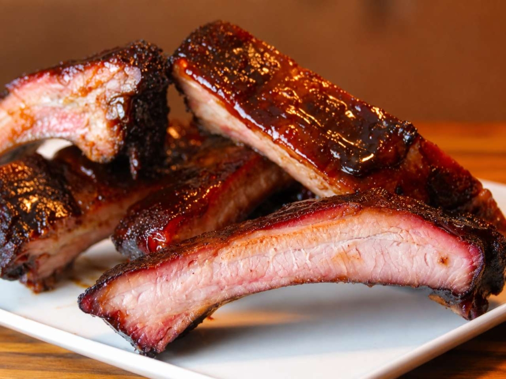 Sliced smoked BBQ ribs stacked on a plate.