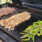 Cheesesteak ingredients cooking on a Flatrock griddle