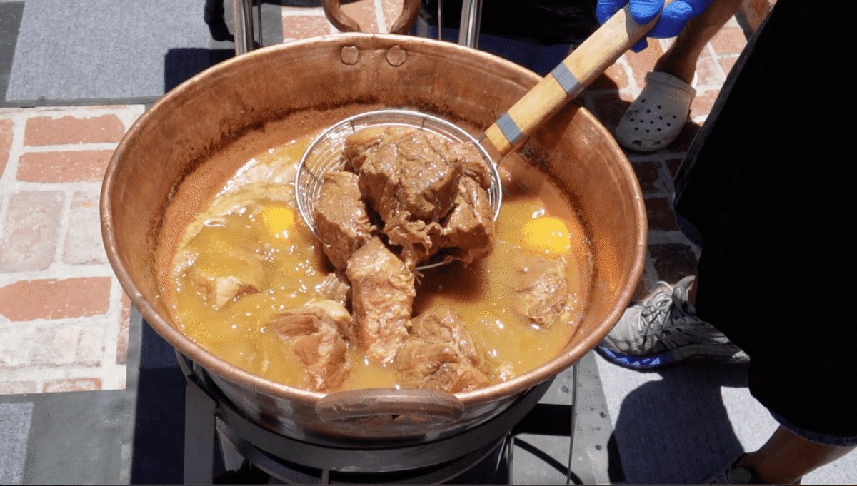 pork cubes simmering in a copper pot.