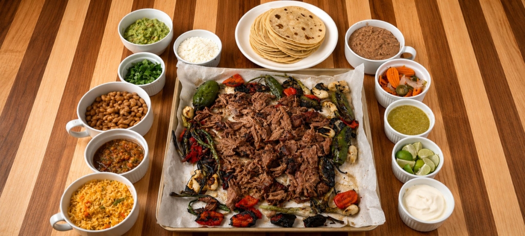 Shredded beef shank on a platter surrounded by different taco fxings.