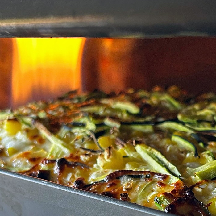 Detroit-style pizza being placed into the pizza oven