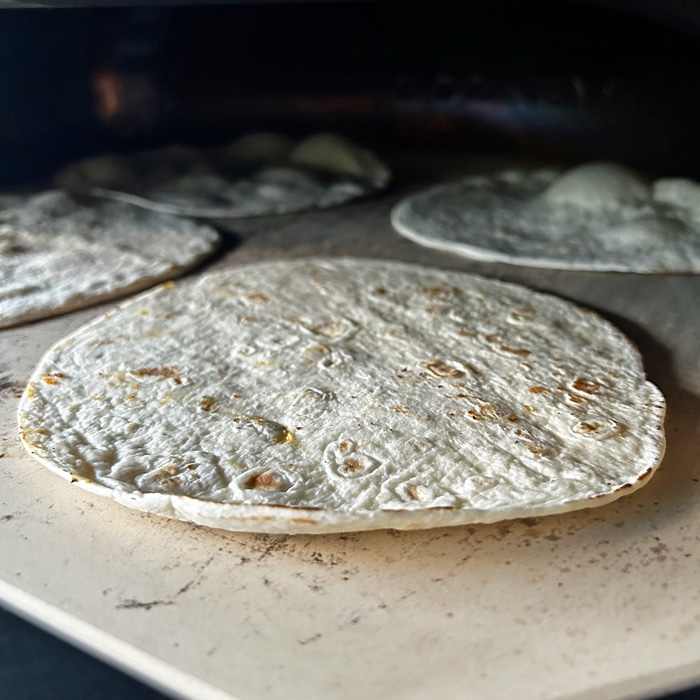 Pan of tortillas entering the pizza oven