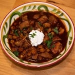pozole rojo in a decorative bowl garnished with sour cream and cilantro