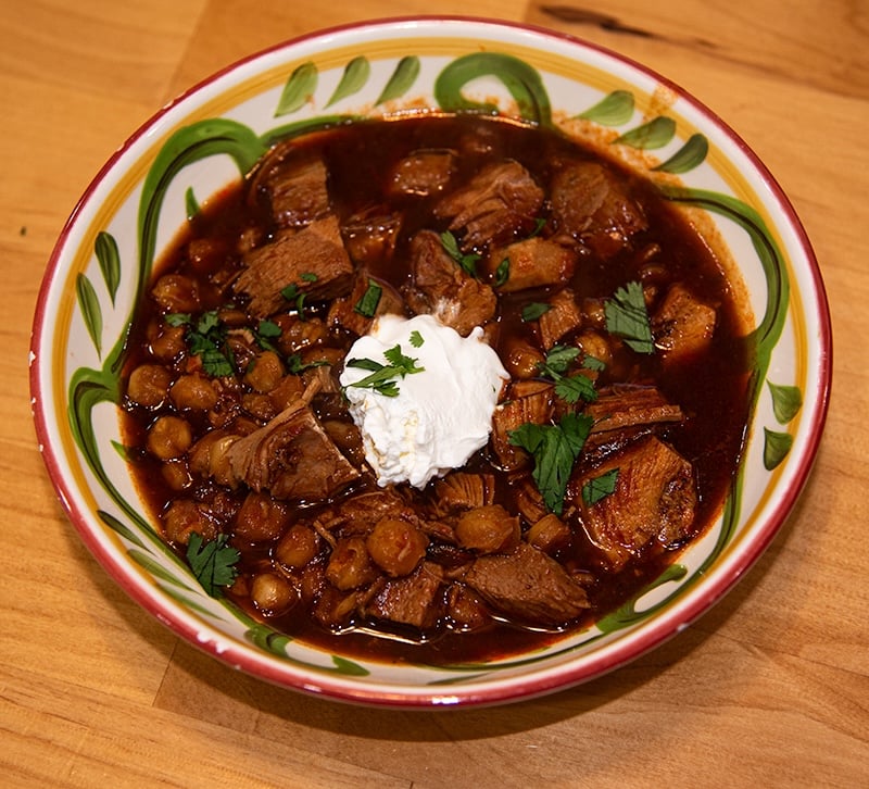 pozole rojo in a decorative bowl garnished with sour cream and cilantro