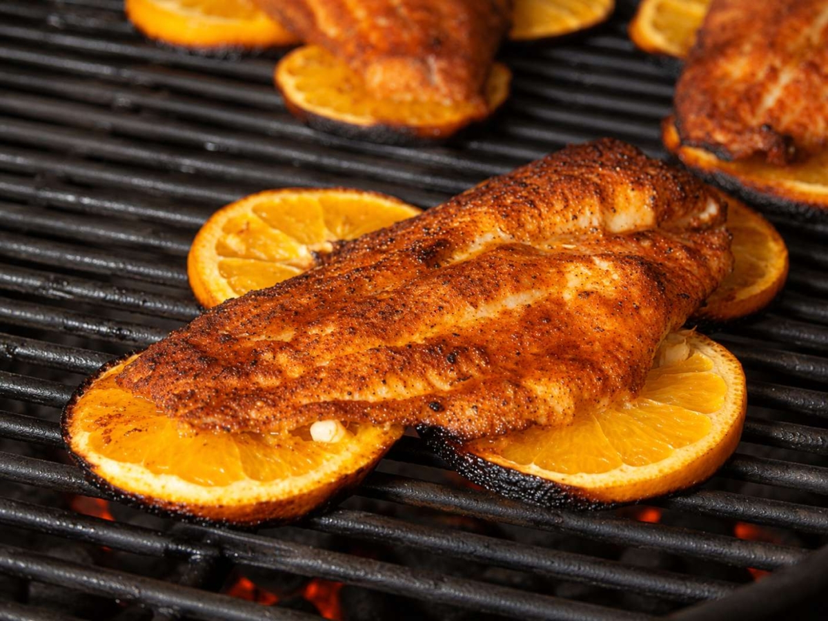 Grilling catfish fillet on orange slices.