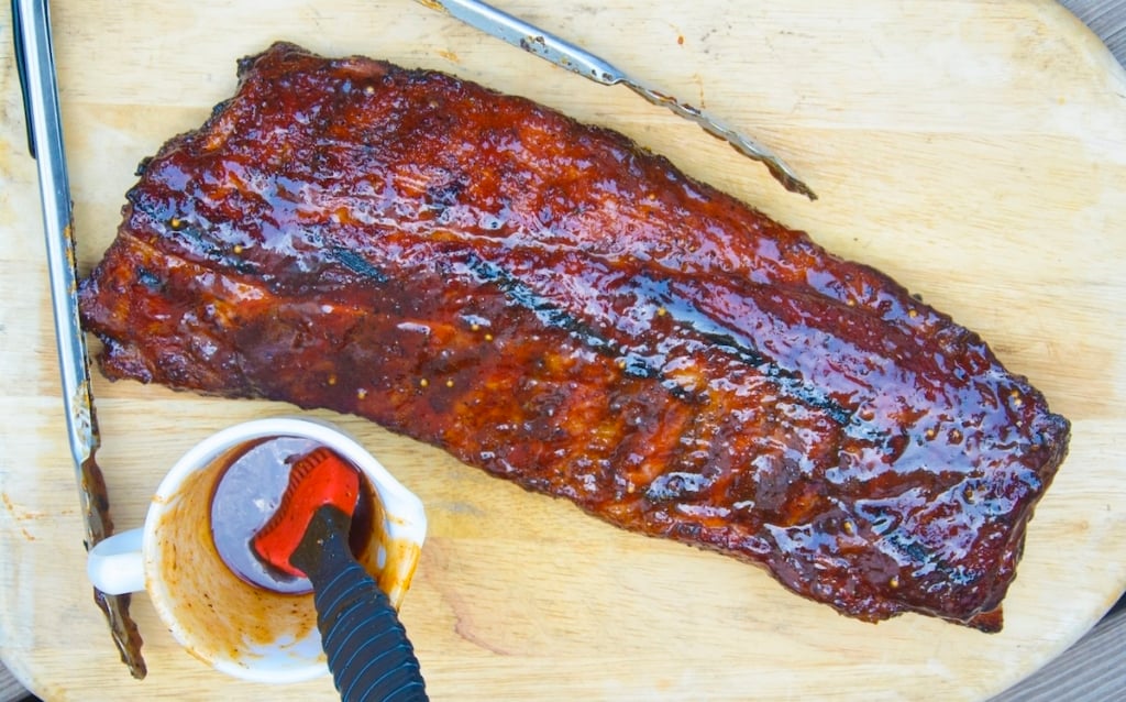 rack of ribs and sauce on a cutting board