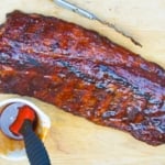 rack of ribs and sauce on a cutting board