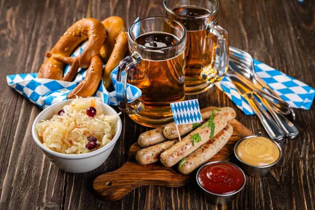 Oktoberfest table with beer, pretzels, sauerkraut, bratwurst and mustard