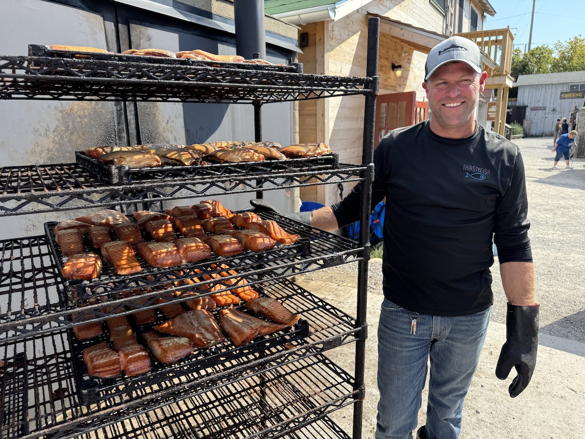 Mike Burda from Carlsons Fish and Smokehouse standing next to a rack of smoked fish.