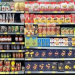 Processed food including dried pasta and canned tomatoes on a grocery store shelf
