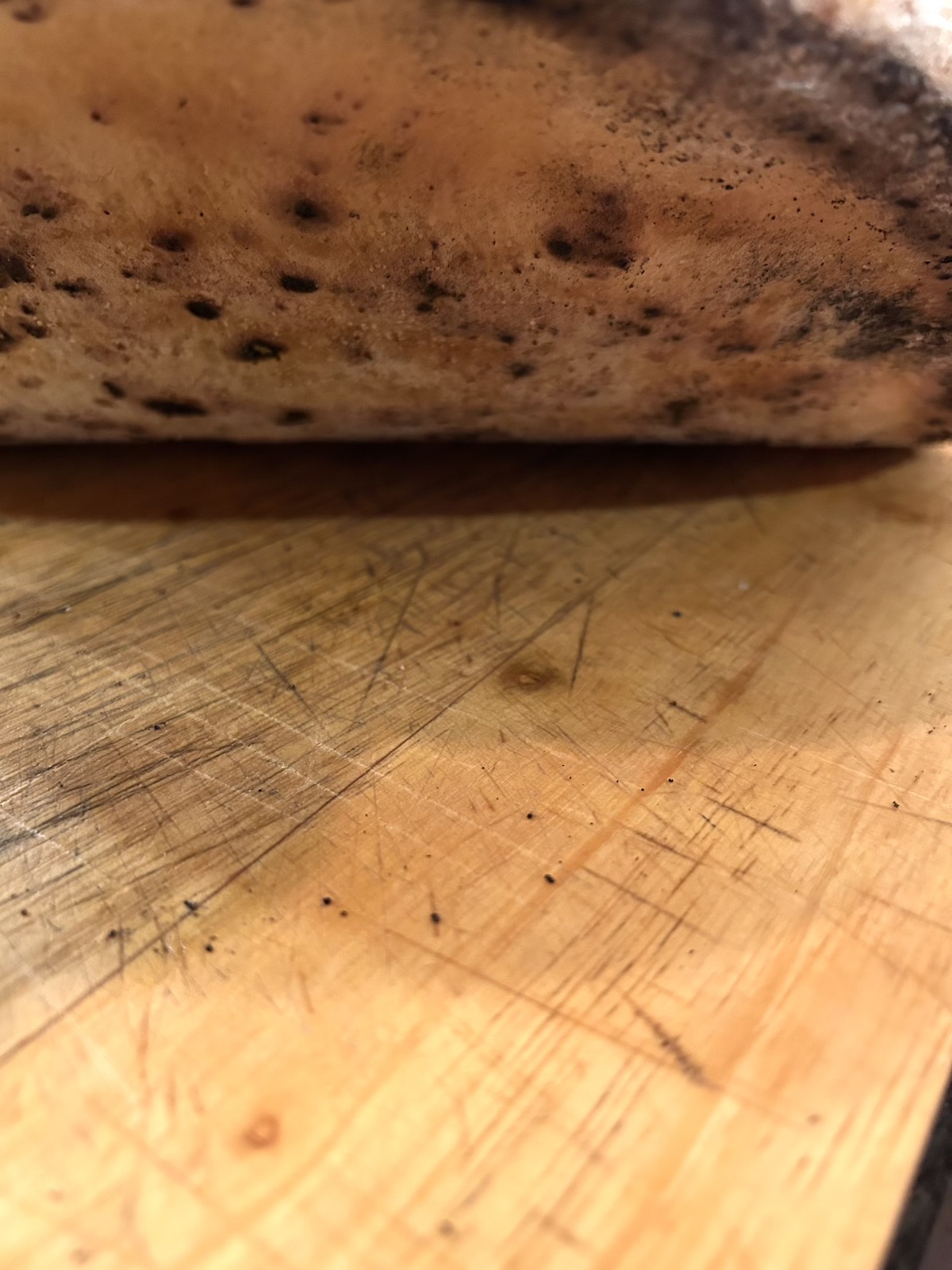 Closeup of the underside of a pizza showing it browned but not burnt