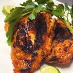 ancho lime grilled chicken thighs on a white plate with fresh cilantro