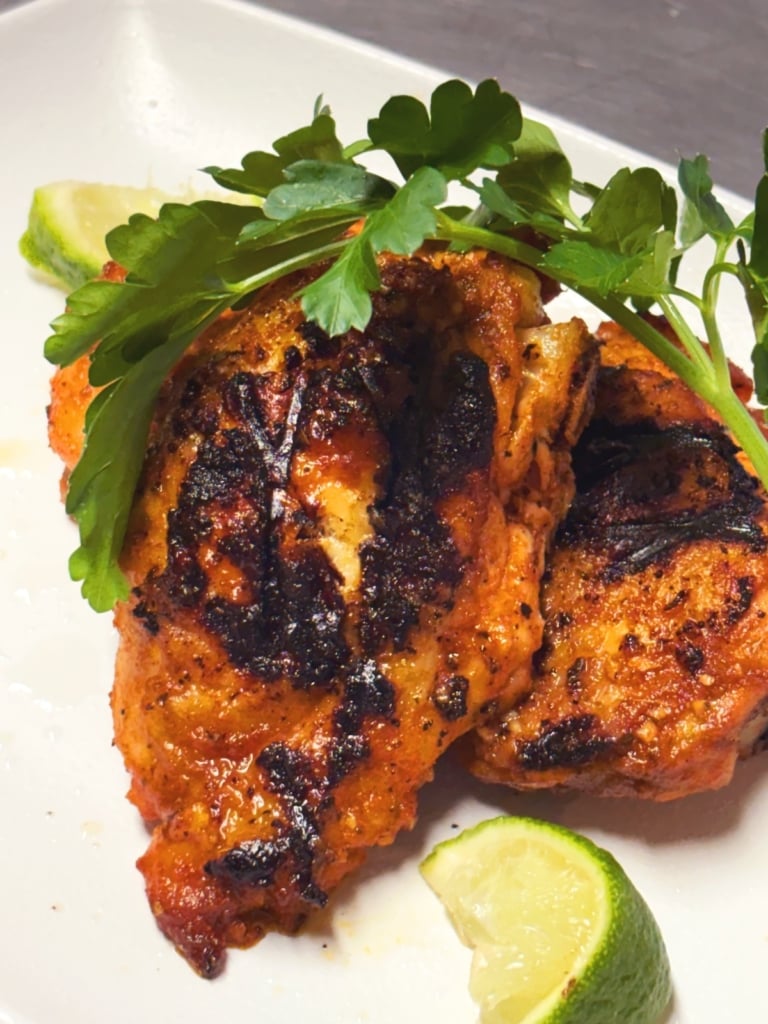 ancho lime grilled chicken thighs on a white plate with fresh cilantro