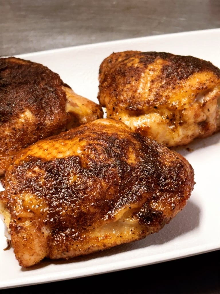 spice rubbed smoked chicken thighs on a white plate