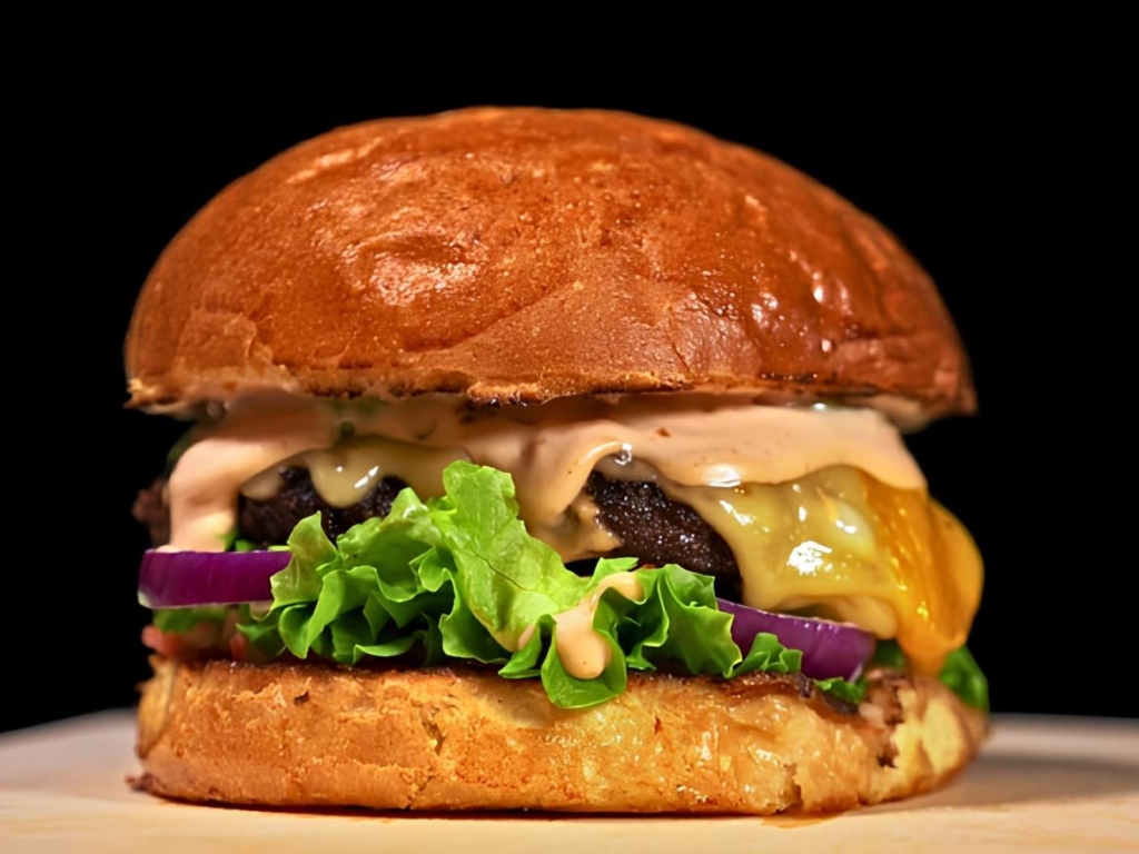 Burger with Big Mac Sauce and lettuce on bun on wooden board.