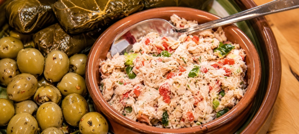 Provencal smoked fish spread in a bowl alongside olives and stuffed grape leaves.