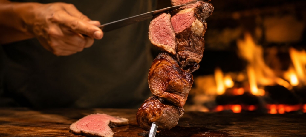 Grilled picanha steaks being sliced from a skewer.