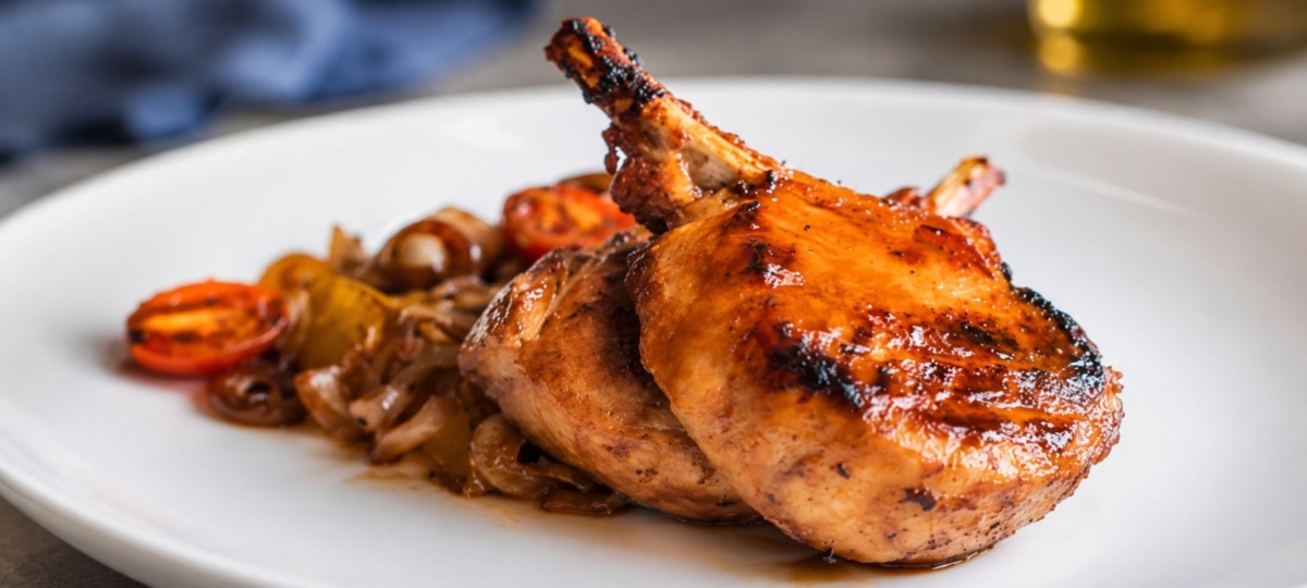 Two grilled porkchops on a plate.