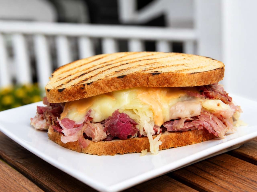 Plated Reuben sandwich with corned beef, cheese, and sauerkraut.