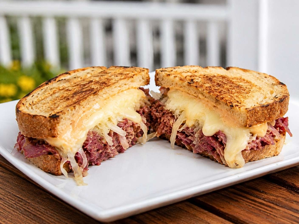 Plated Reuben sandwich with corned beef, cheese, and sauerkraut.