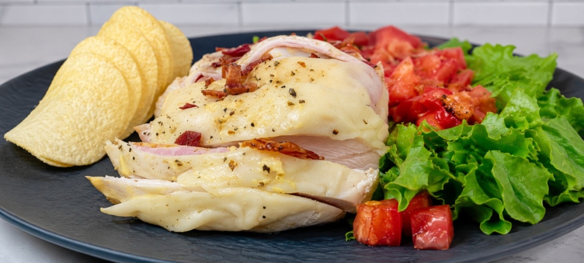 Plated stuffed chicken breast with Pringles and salad.
