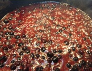 Blueberry BBQ sauce recipe in a pot showing the whole blueberries.