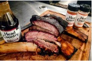 Texas beef short ribs on a cutting board with Head Country barbecue sauce.
