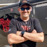 Doug Sheiding standing arms folded, sunglasses on.