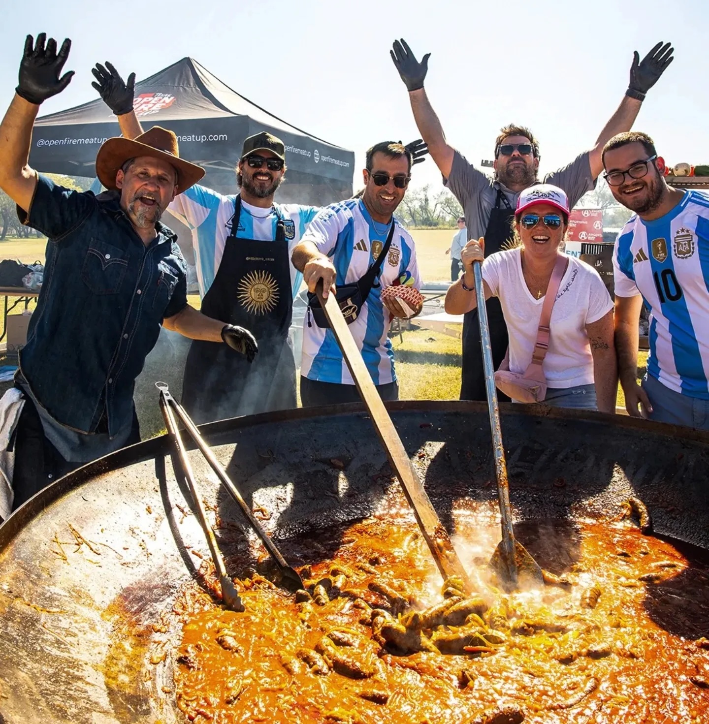 Pitmasters standing around a giant cauldron of food at the Texas Open Fire Meat Up.