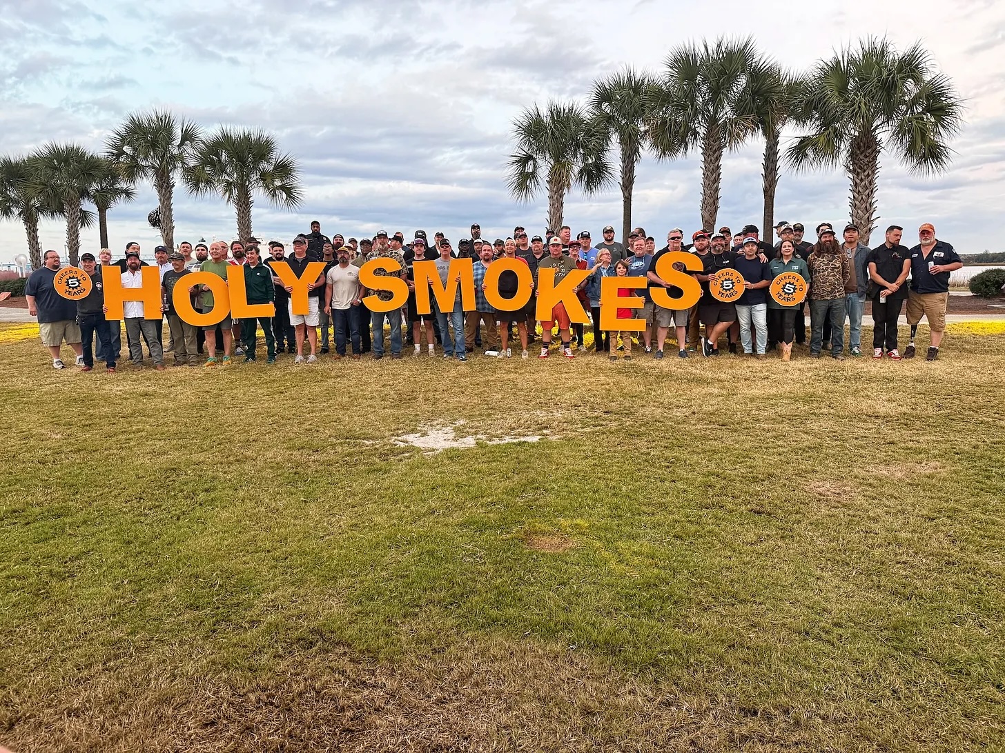 Attendees at the Holy Smokes Lowcountry BBQ Festival holding giant letters that spell out "Holy Smokes."