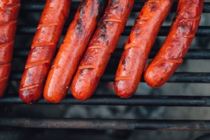 hot dogs lined up on a grill grate.