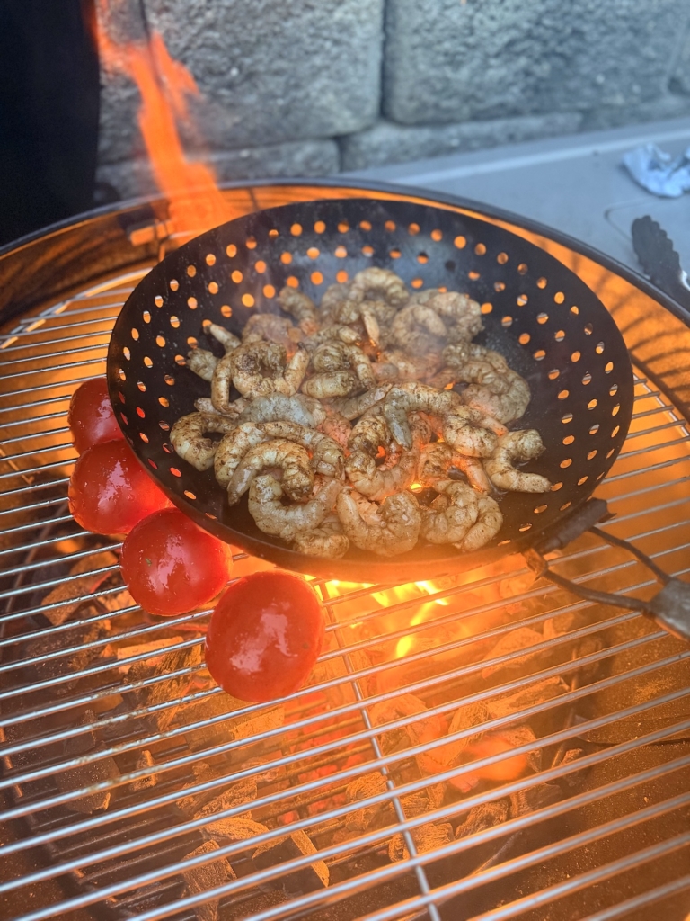 Shrimp in a grill pan with fresh tomatoes on the grill grate on a Weber 22-inch Performer Smart Charcoal Grill.