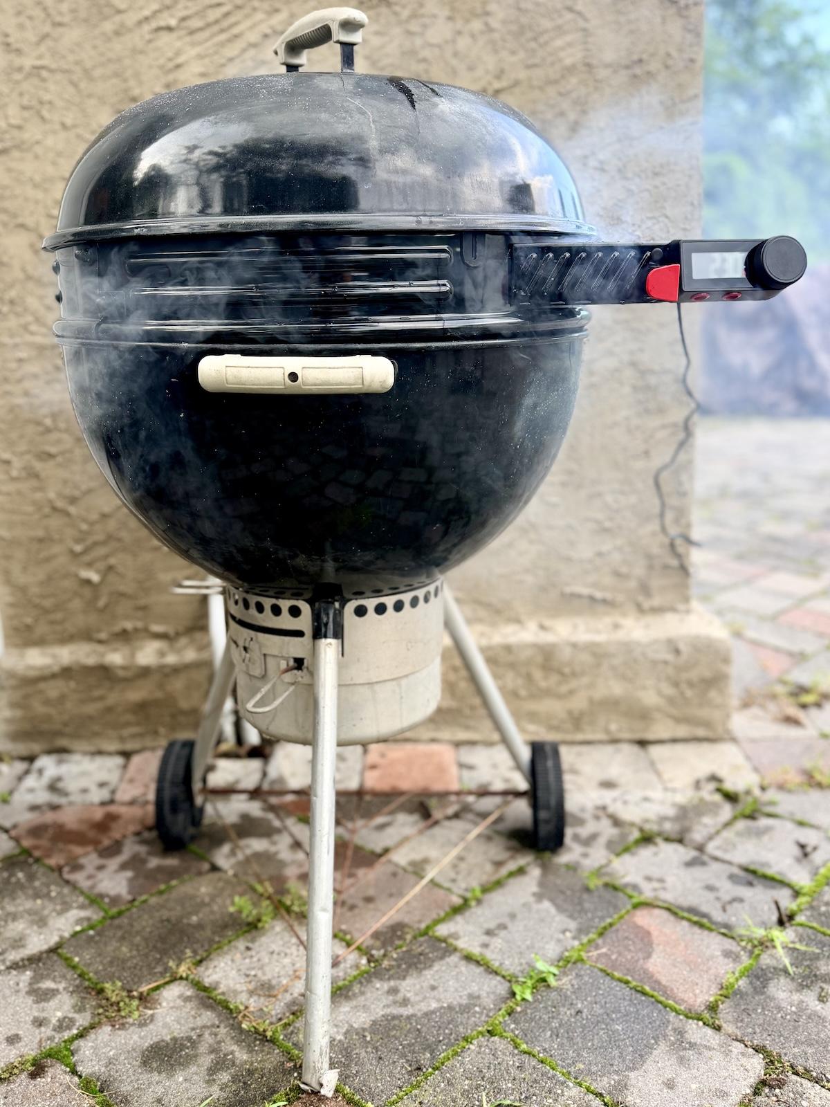 Weber Kettle Smart Ring installed on a Weber charcoal grill in use with smoke coming out of the grill.