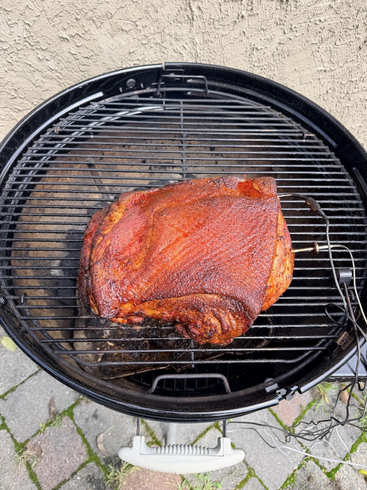 Pork shoulder cooking on a charcoal grill with Weber Kettle Smart Ring installed.